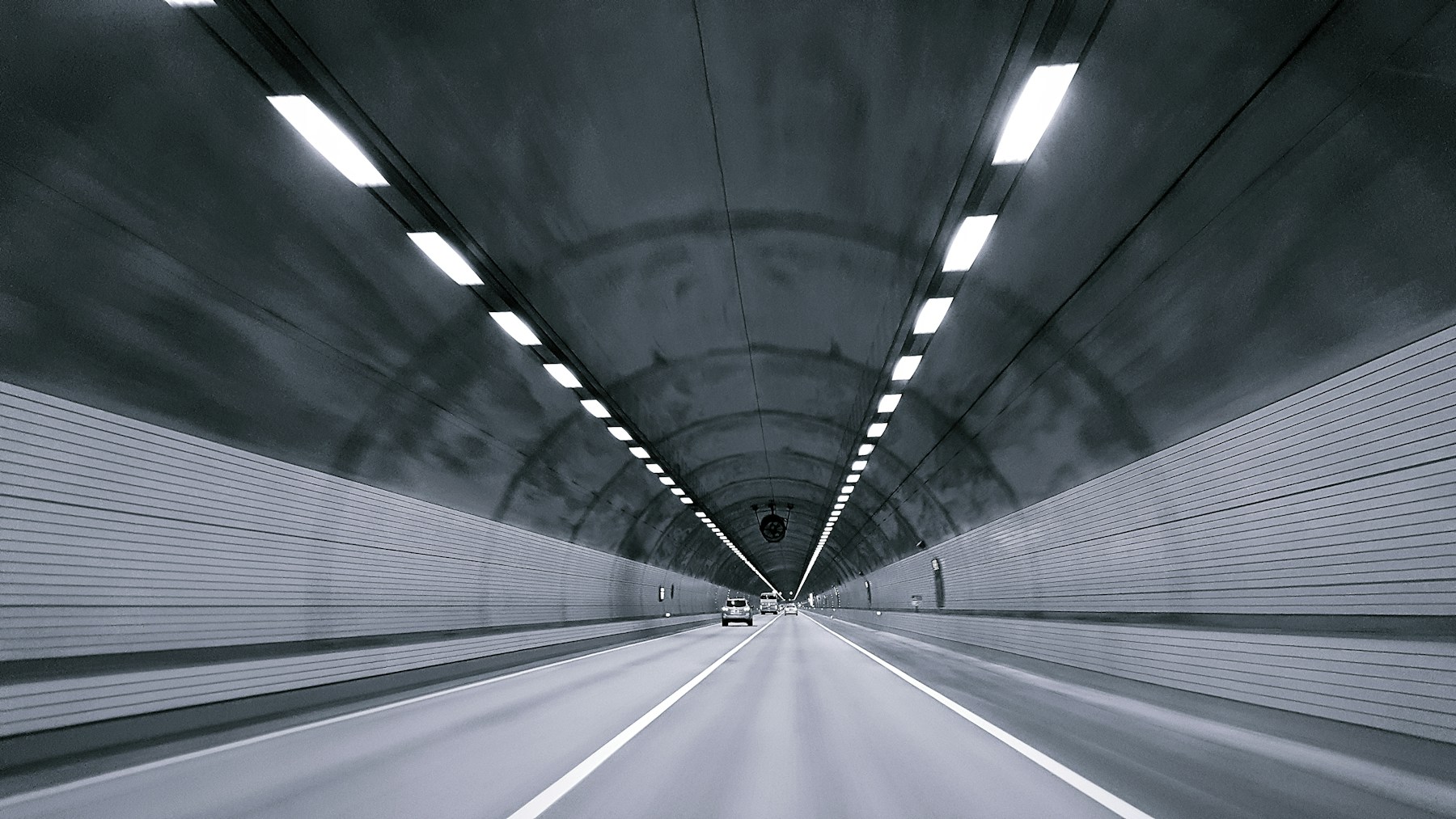 Beleuchteter Straßentunnel mit Fahrbahn und Fahrzeugen